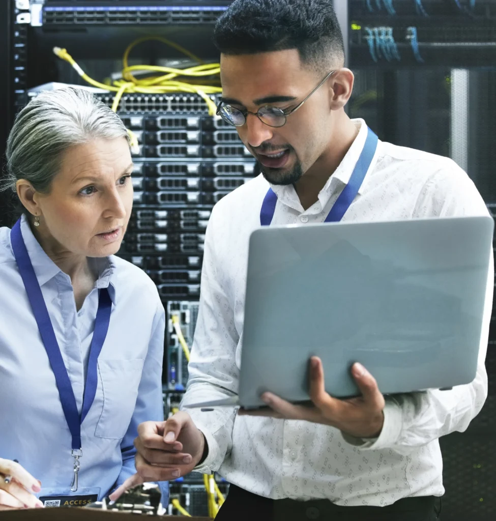 Two people in a room with one holding a laptop