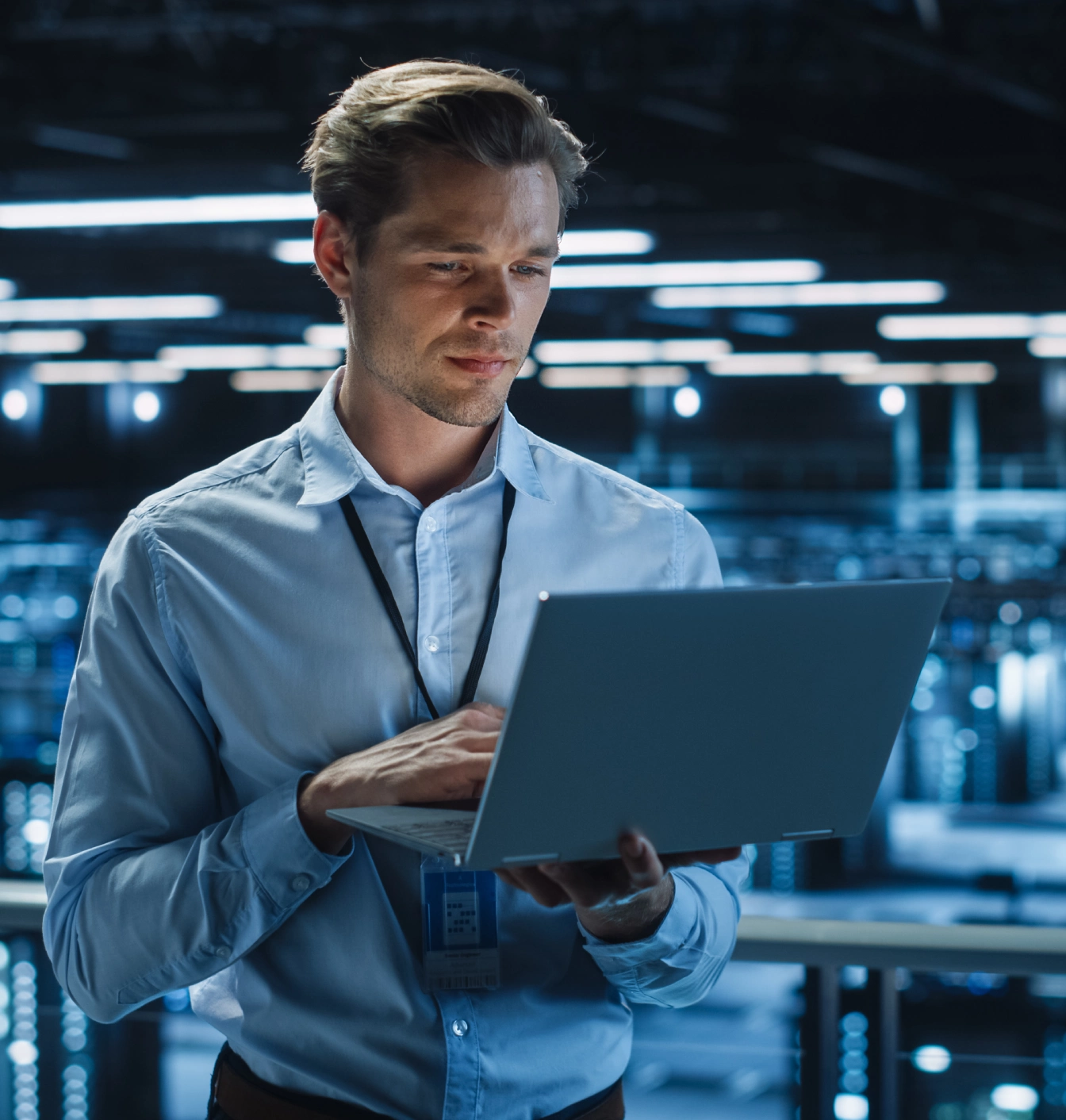 A man in blue shirt holding a laptop.