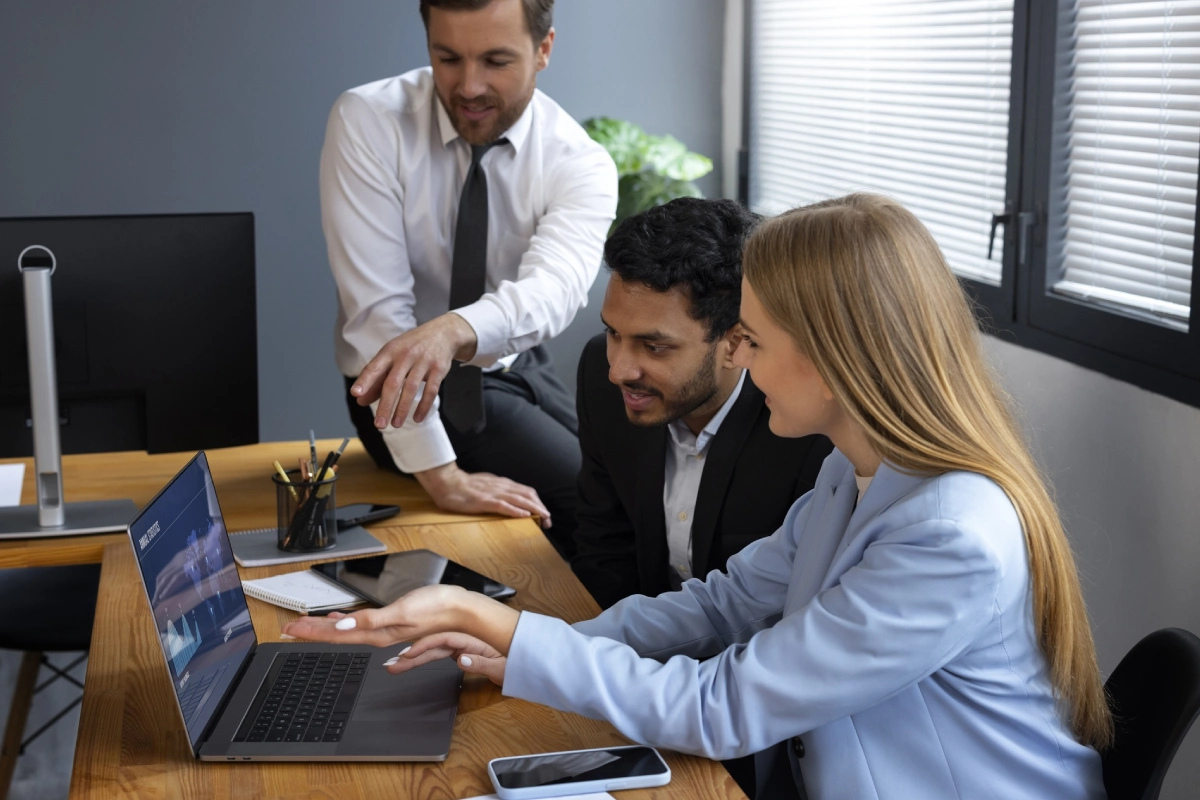 A group of people sitting around a table with laptops.