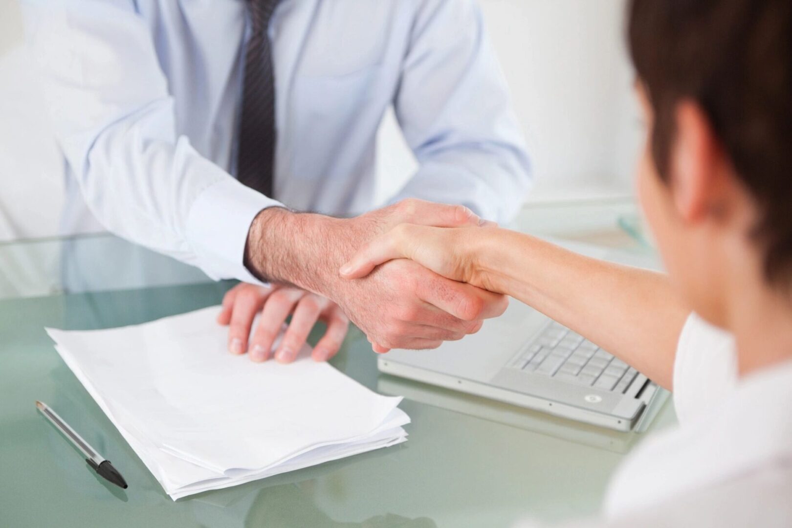 A man and woman shaking hands over papers.