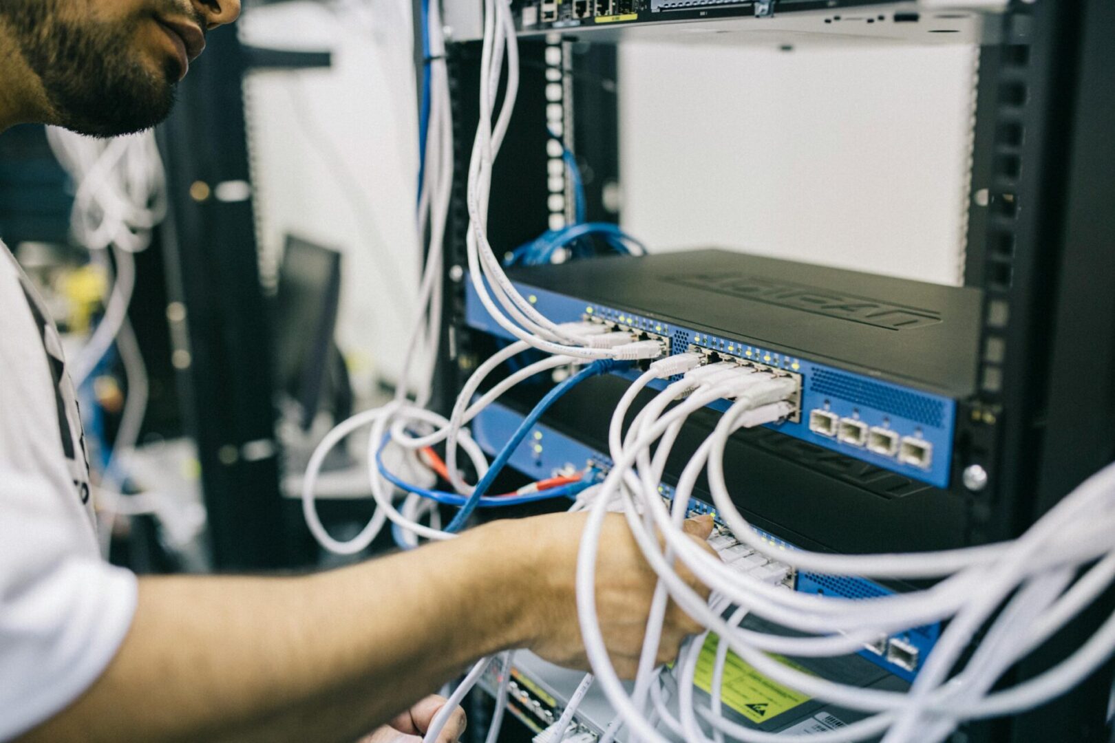 A person is holding wires in front of a computer.