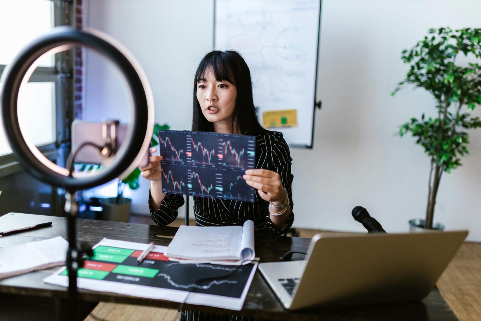 A woman sitting at a desk holding up a picture.