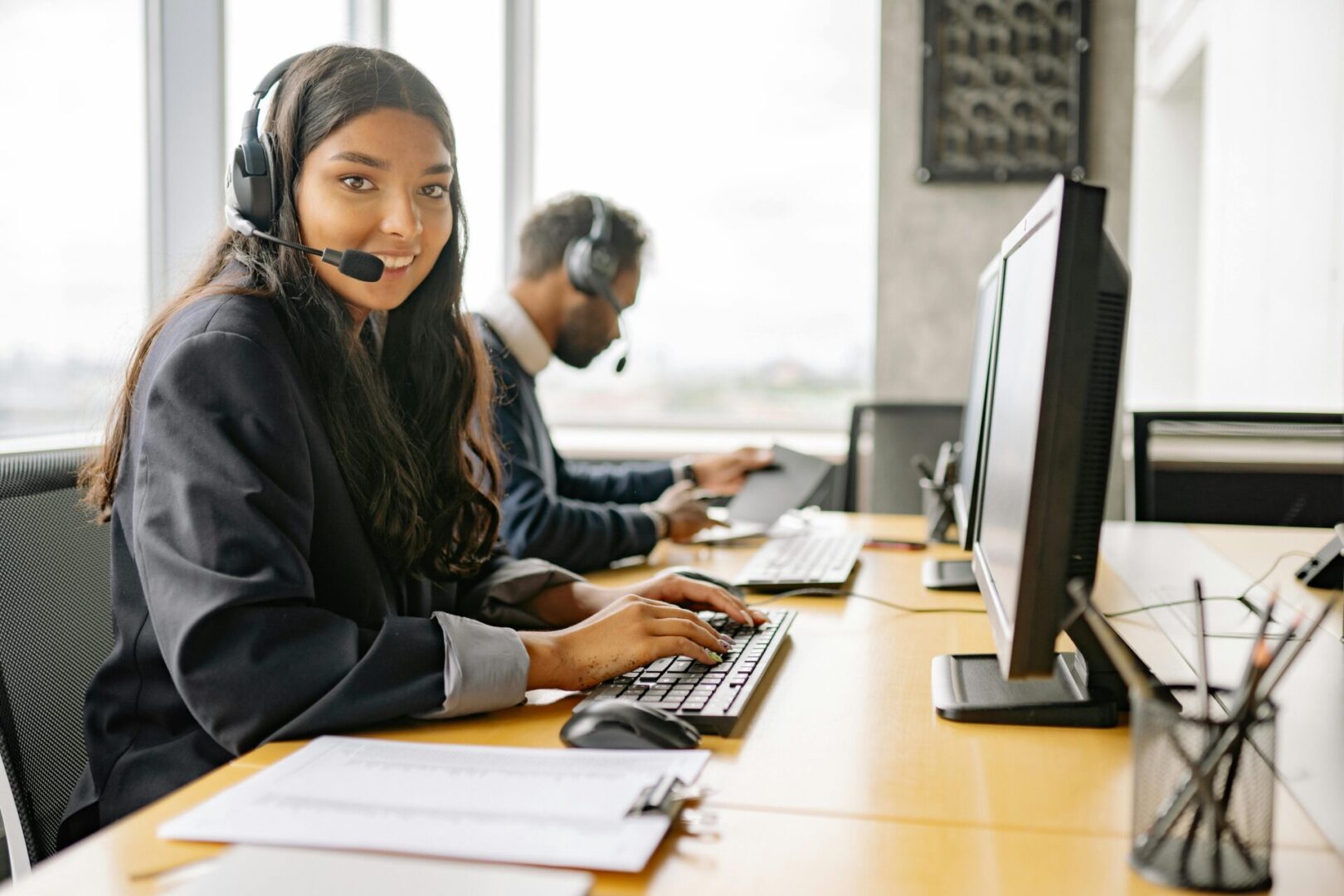 A woman with headphones on sitting at a desk.