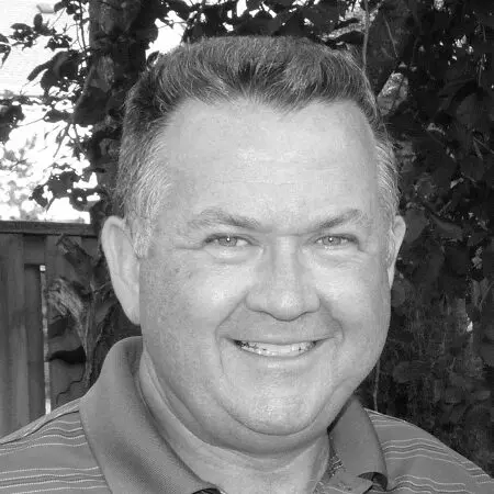 A black and white photo of a man smiling.