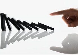 A hand is pointing to the domino effect.