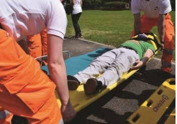 A group of people in orange and white shirts are on the ground.