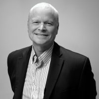 A man in a suit and tie smiling for the camera.