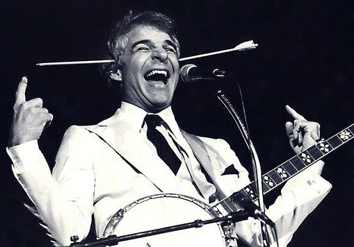 A man in white jacket holding a banjo and singing.