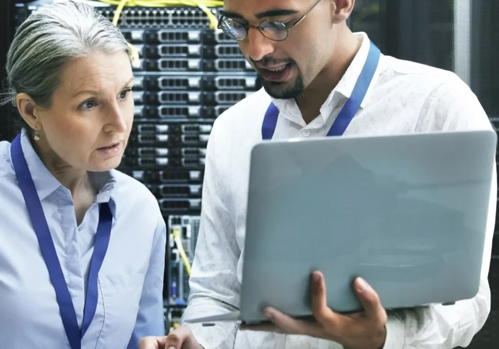 Two people in a room with one holding a laptop