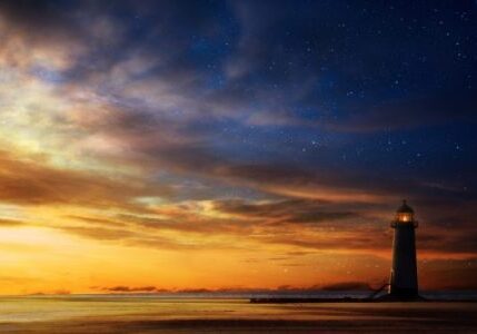 A lighthouse on the beach at sunset.